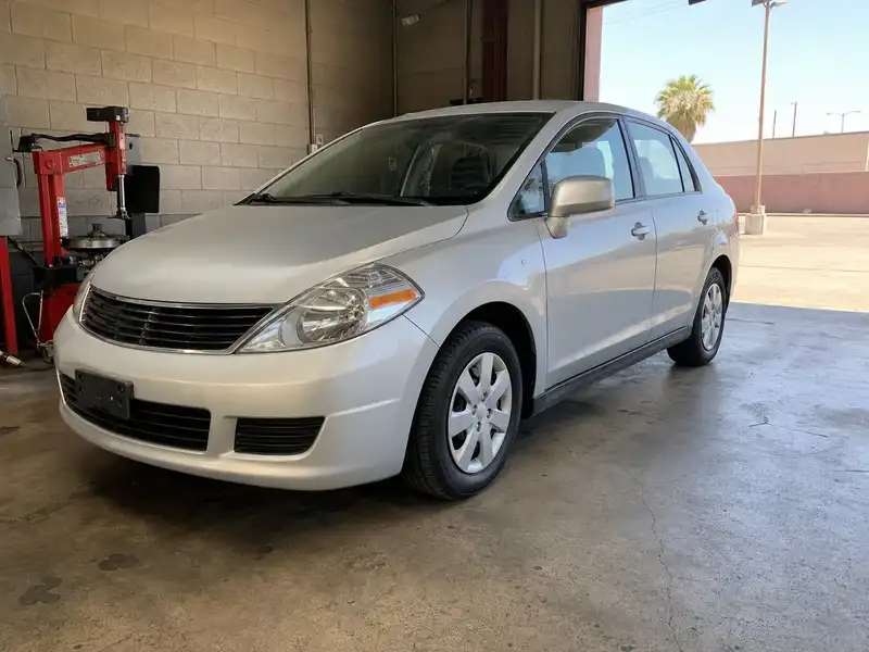 Silver compact sedan with new tires in a shop bay