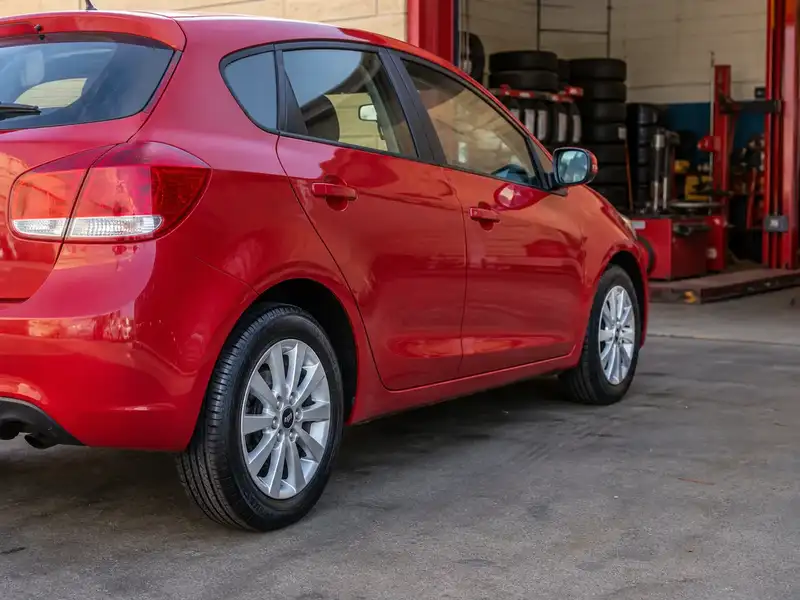 Red hatchback with new tires installed at the shop