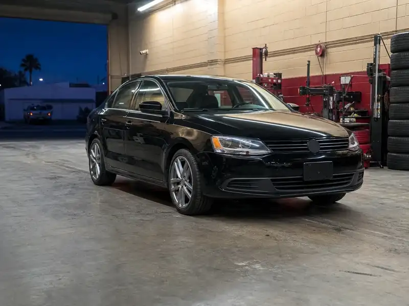 Black sedan with new tires in a lit shop bay