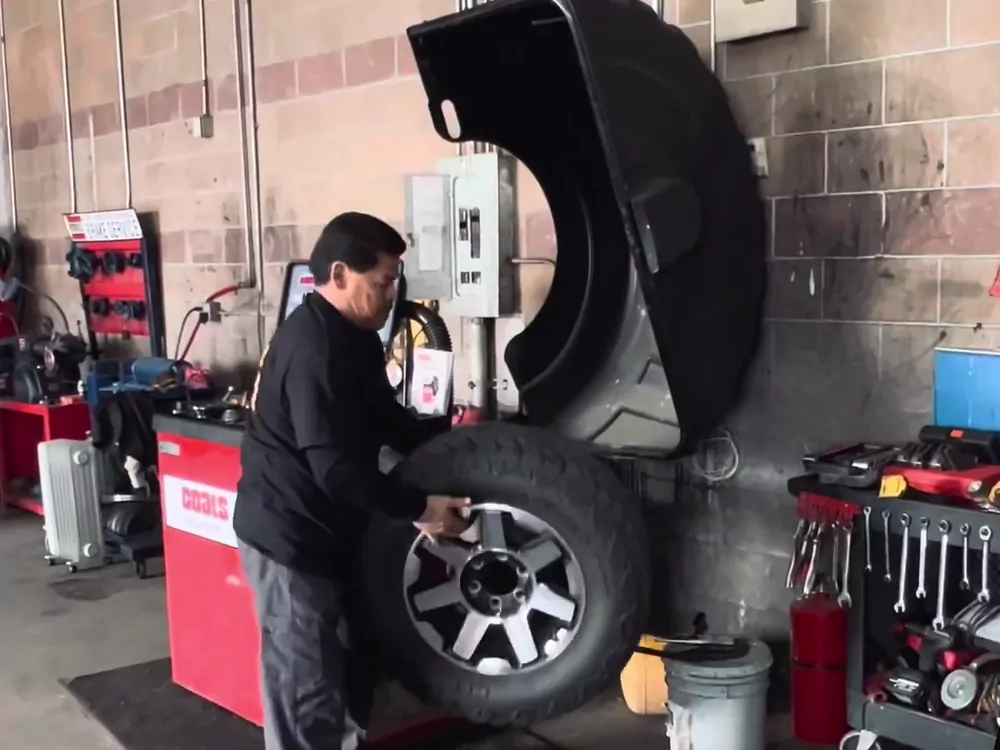 Kain's Tires technician mounting a wheel on the shop's balancer